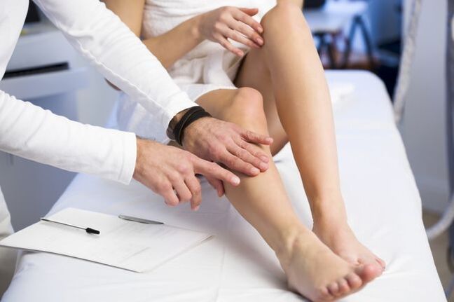 The doctor examines the leg with varicose veins